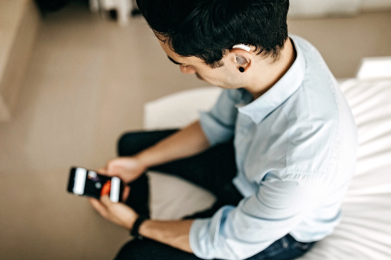 A person wearing a hearing aid and using a smartphone