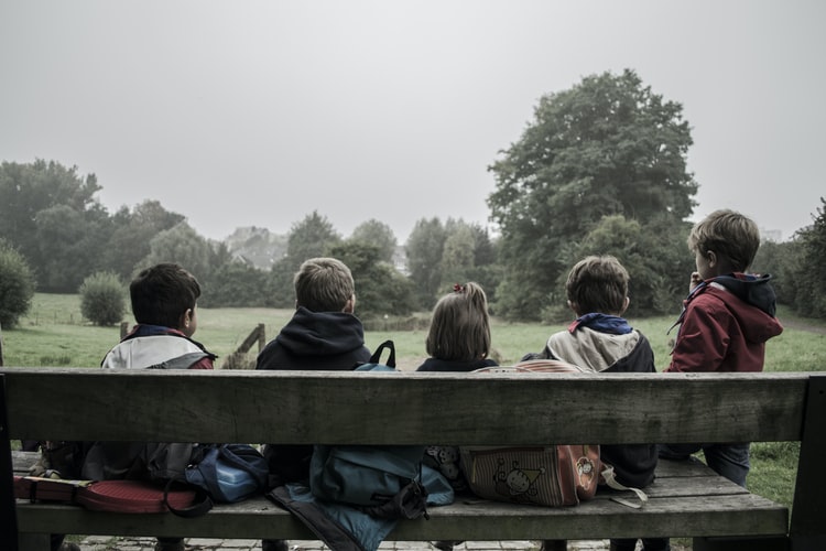 Children sitting together outside on a bench.