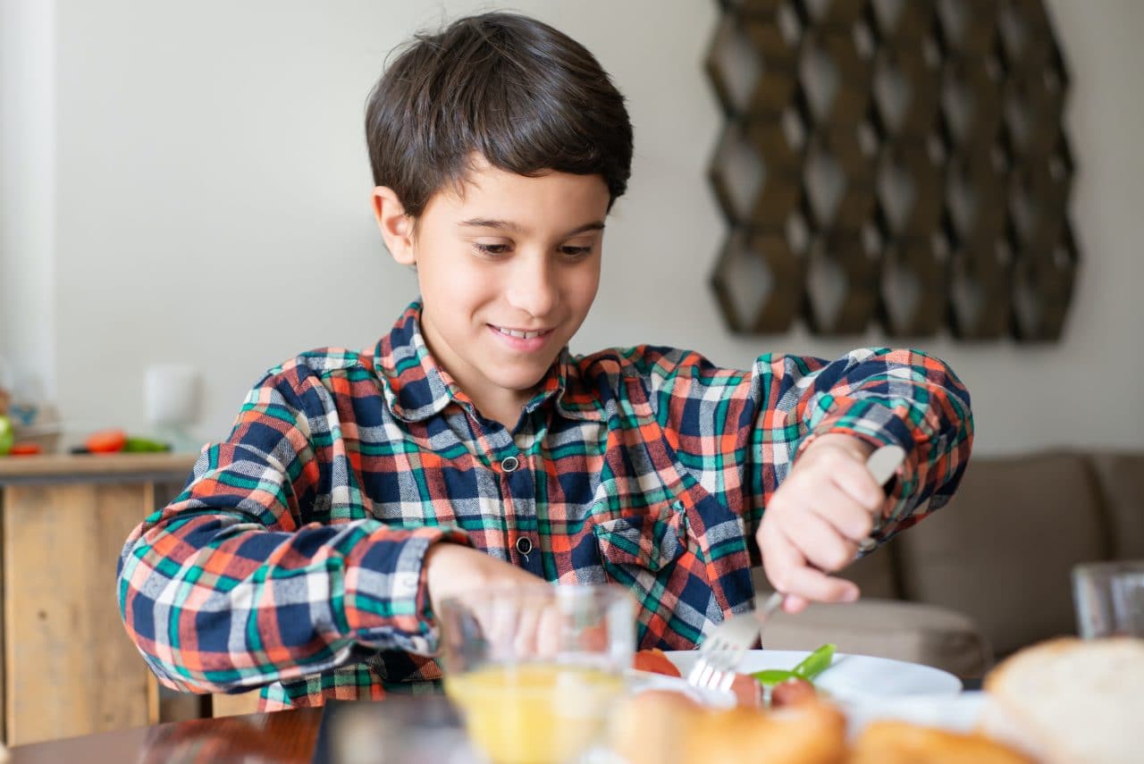 Young boy eating at the table.