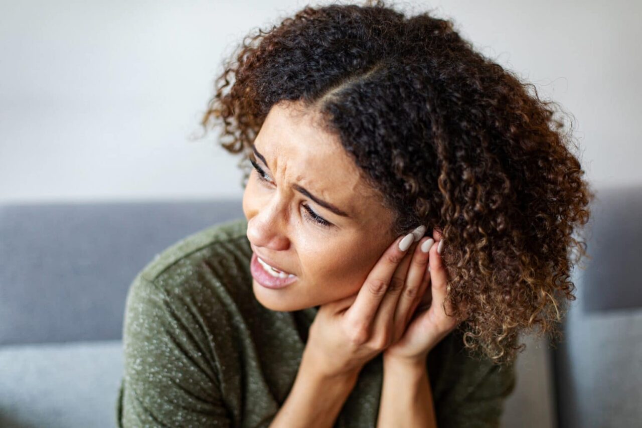A woman experiencing pain from a ruptured eardrum