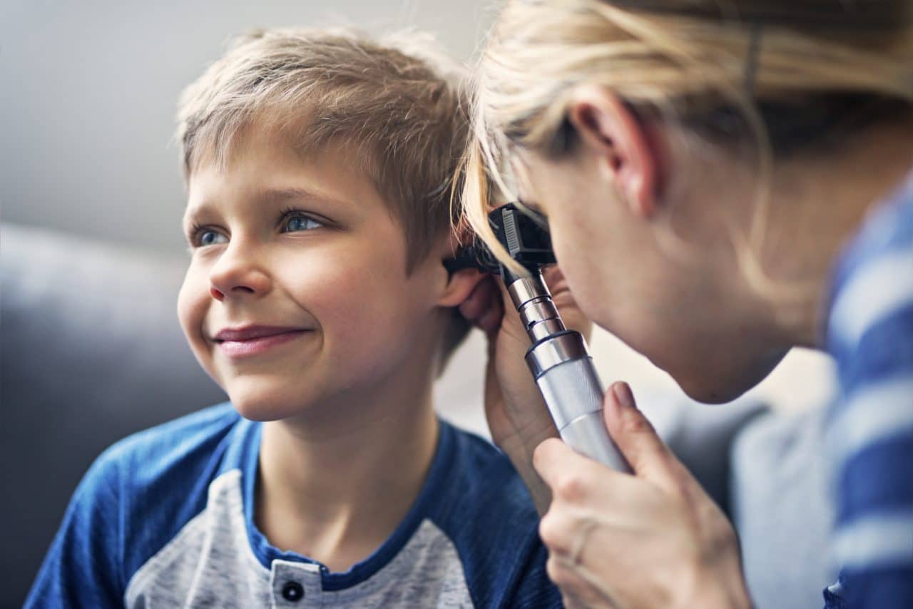 Happy little boy having his ears examined by an ENT.