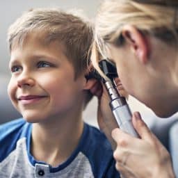 Happy little boy having his ears examined by an ENT.