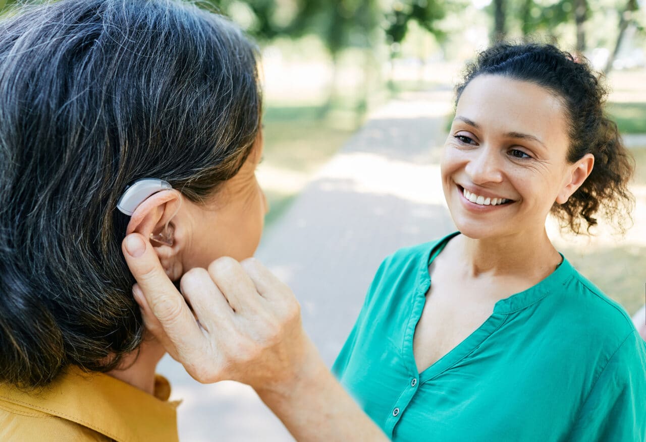 Woman with a hearing aid talking to her friend outside.