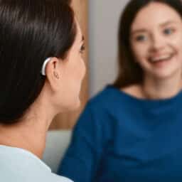 Young woman with a hearing aid talking with her friend at home.