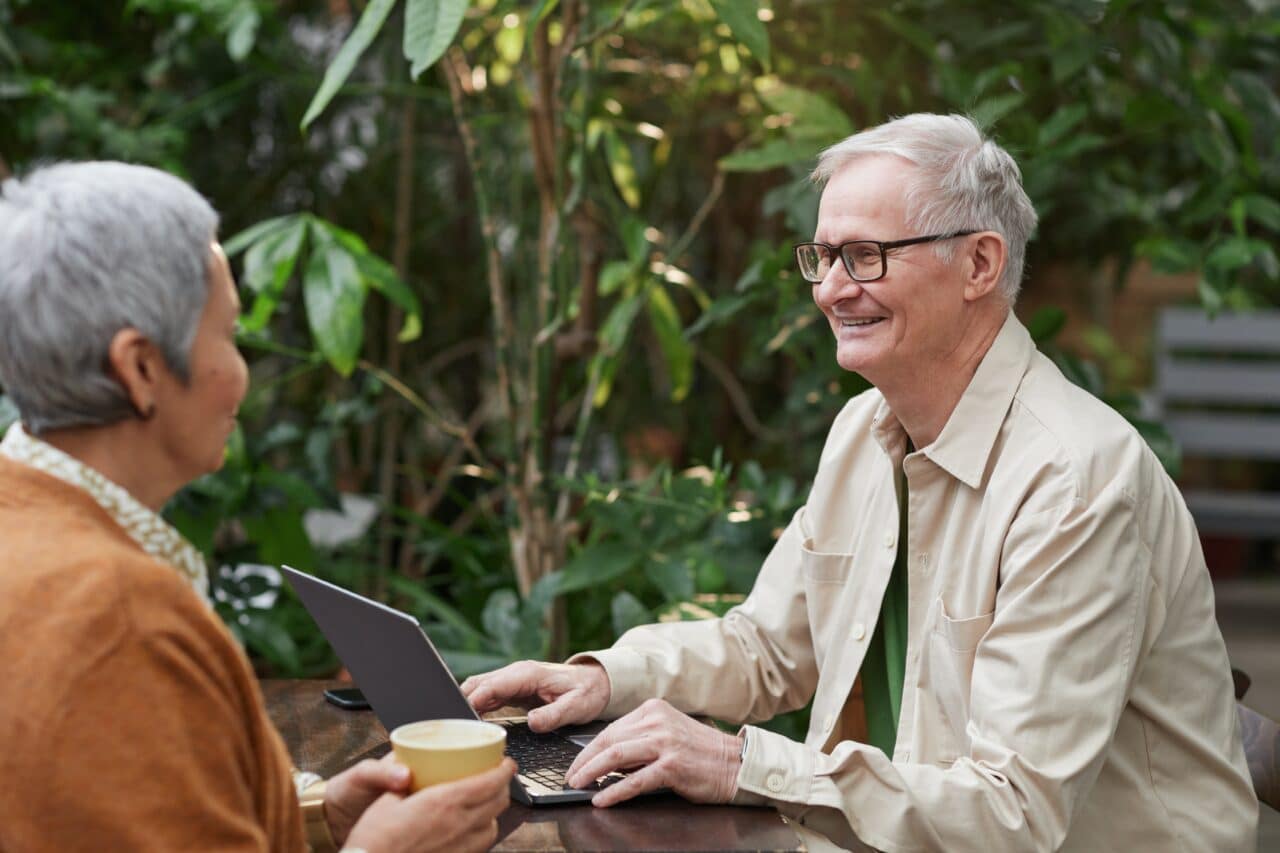 Older couple enjoying a conversation at an outdoor cafe.