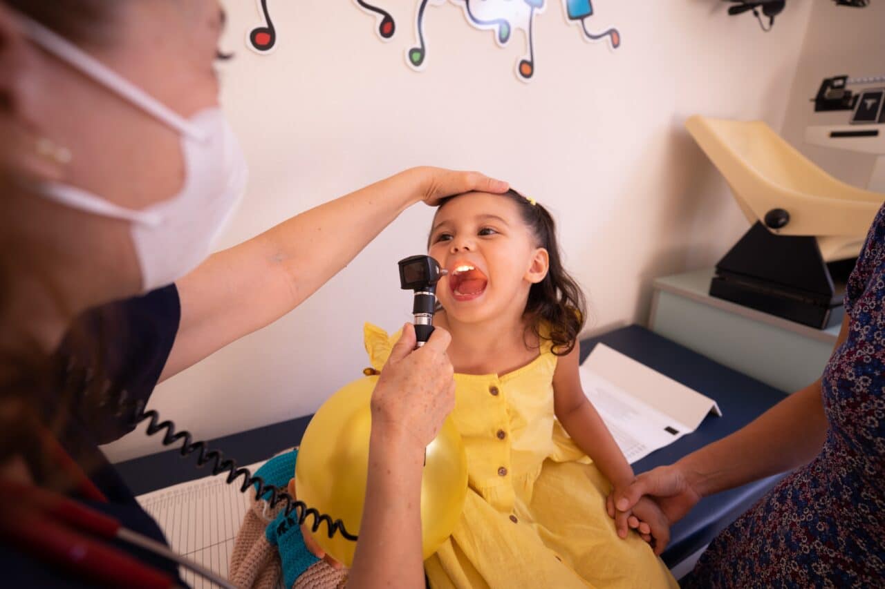 Little girl getting her throat examined at the doctor's office.