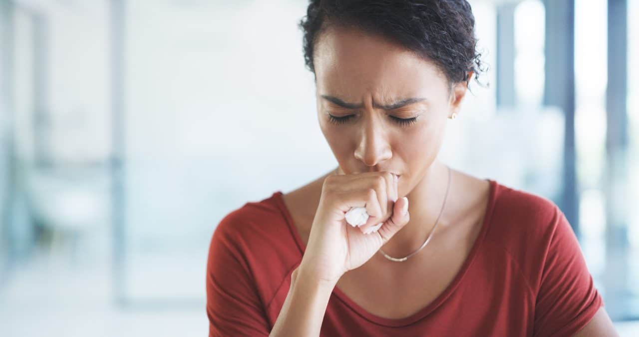 Young woman coughing in an office building.