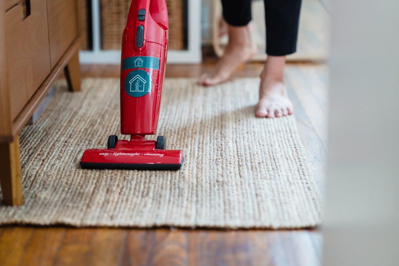 Close-up of a woman vacuuming her carpet at home.