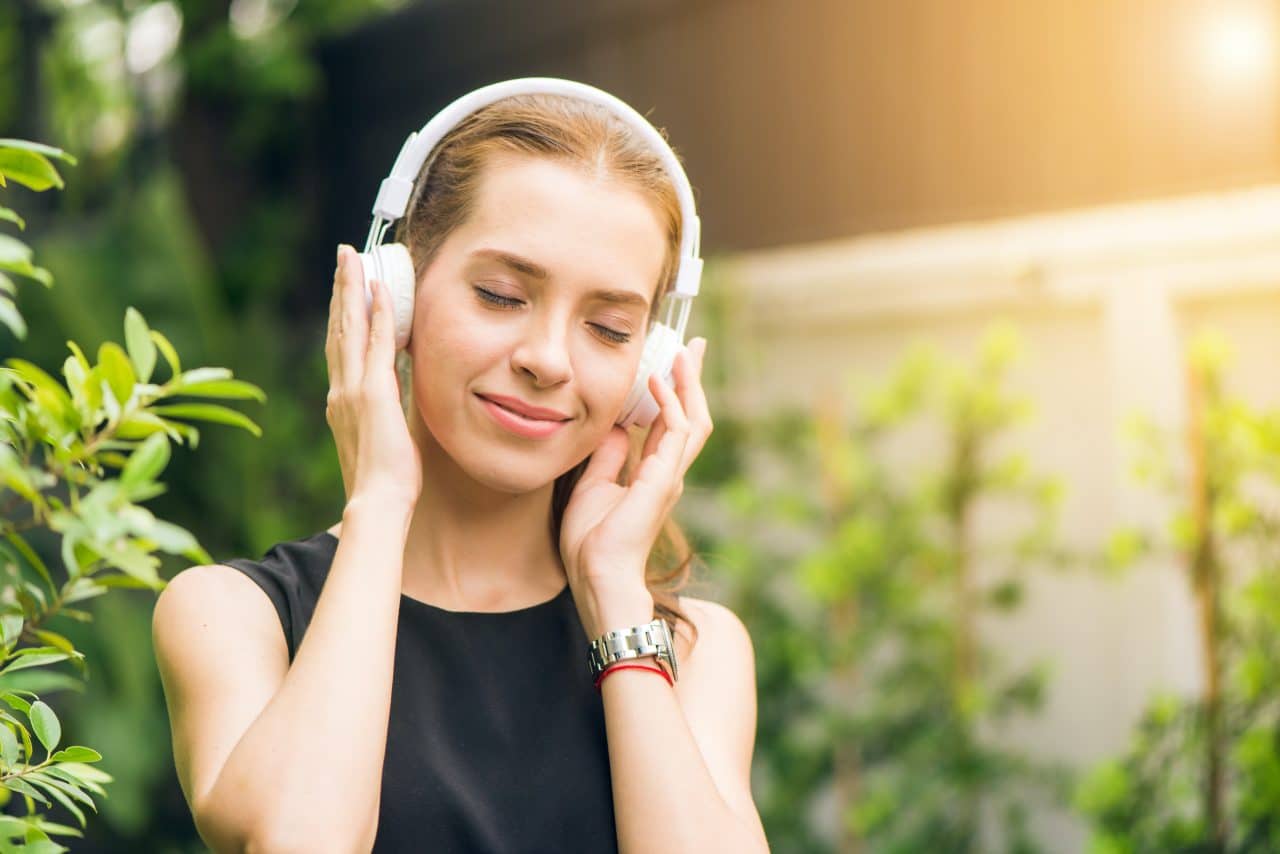 Woman listening to headphones outside.