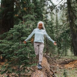 Active senior woman balances on fallen tree