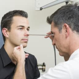 ENT examining a man's nose with an endoscope