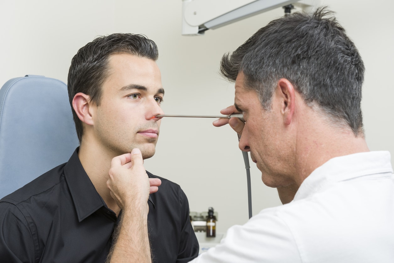 ENT examining a man's nose with an endoscope.