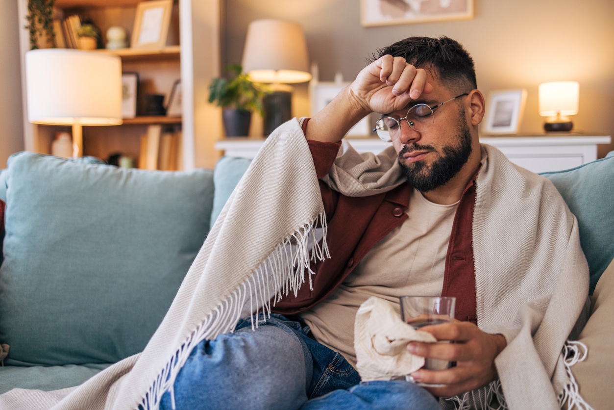 A mid-adult sick man sitting on the sofa in the living room.